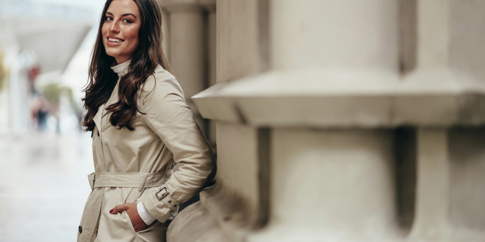 Beautiful young woman posing while outside in a city wearing trench coat