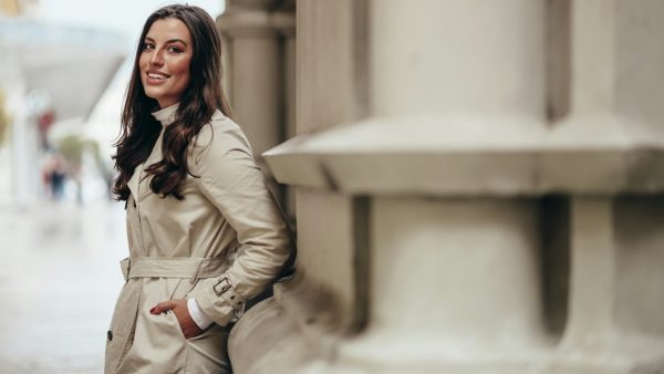 Beautiful young woman posing while outside in a city wearing trench coat