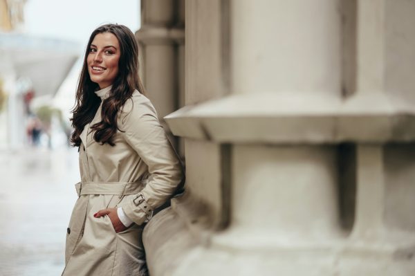 Beautiful young woman posing while outside in a city wearing trench coat