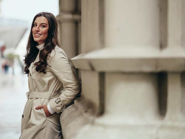 Beautiful young woman posing while outside in a city wearing trench coat