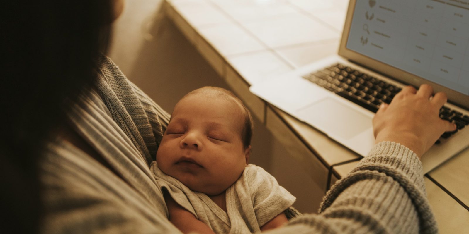 Mother using a computer and holding her baby