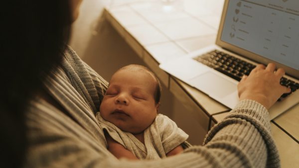 Mother using a computer and holding her baby