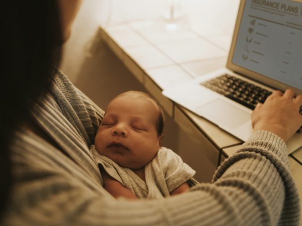 Mother using a computer and holding her baby