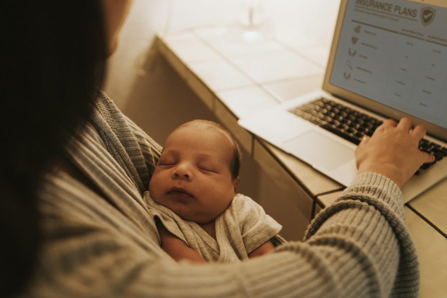 Mother using a computer and holding her baby