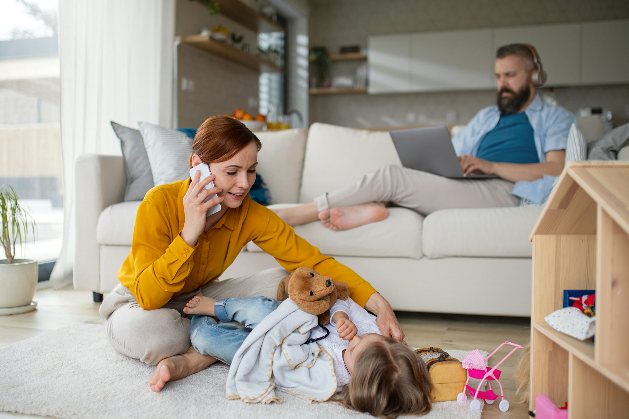 Mother with daughter playing and working at home, everyday life and home office with child concept.