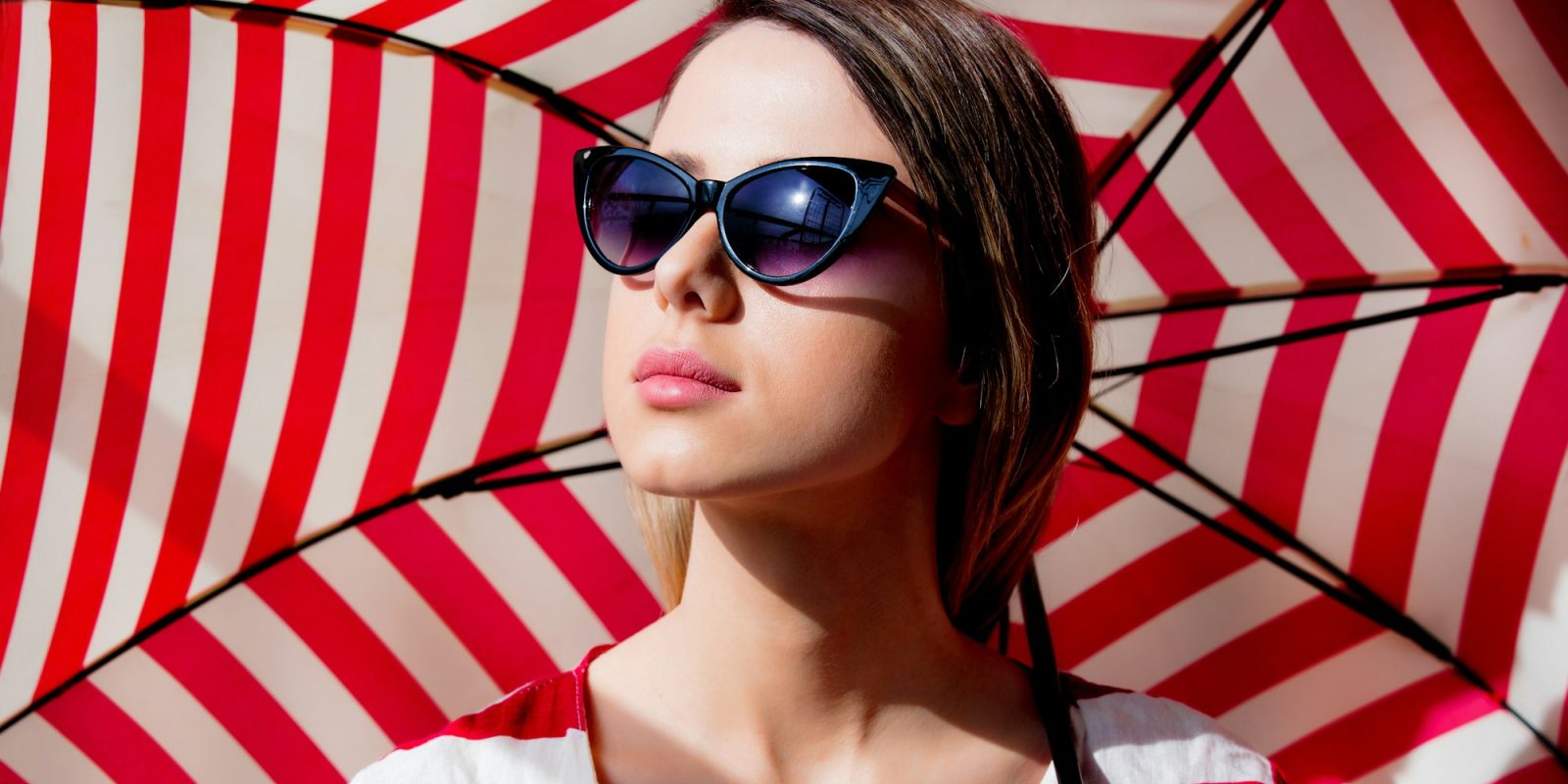 woman in sunglasses with red striped umbrella