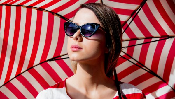 woman in sunglasses with red striped umbrella