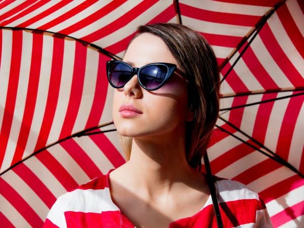 woman in sunglasses with red striped umbrella