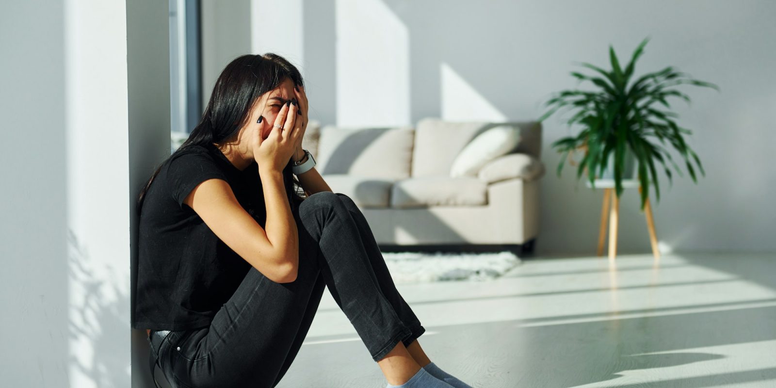 Young woman in casual clothes crying alone at home at daytime