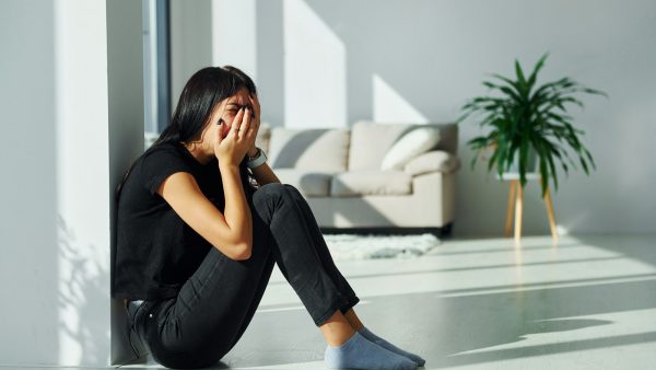 Young woman in casual clothes crying alone at home at daytime