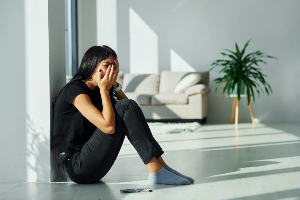 Young woman in casual clothes crying alone at home at daytime