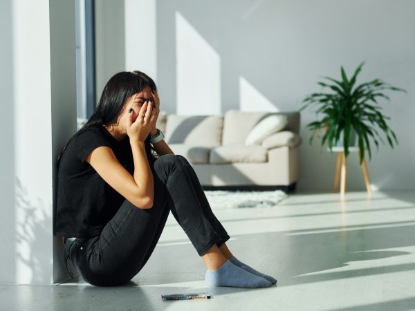 Young woman in casual clothes crying alone at home at daytime